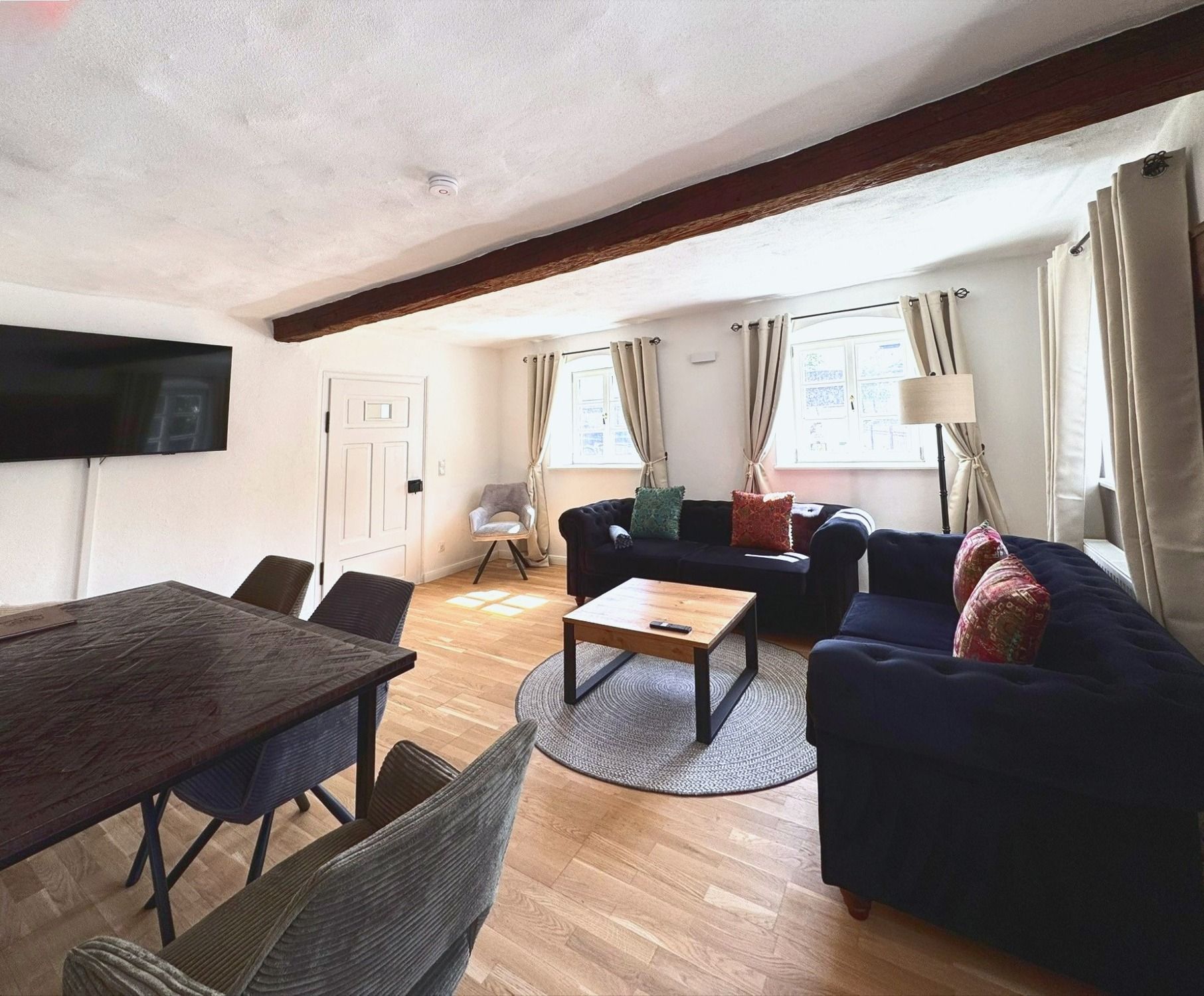 Wohnzimmer mit Esstisch, Smart TV und Sofaecke unter dem Eichenbalken