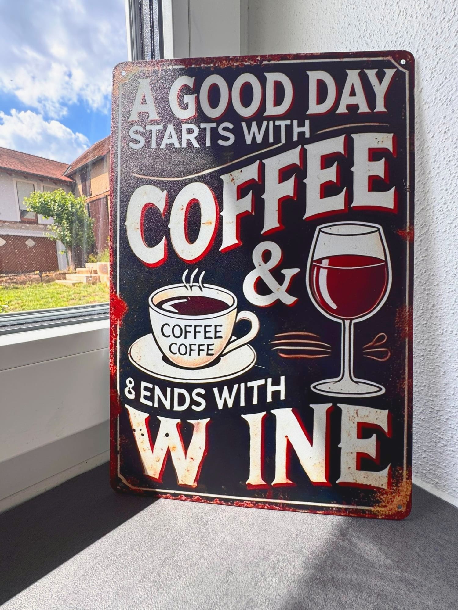 Dekoschild „A good day starts with coffee“ am Fenster