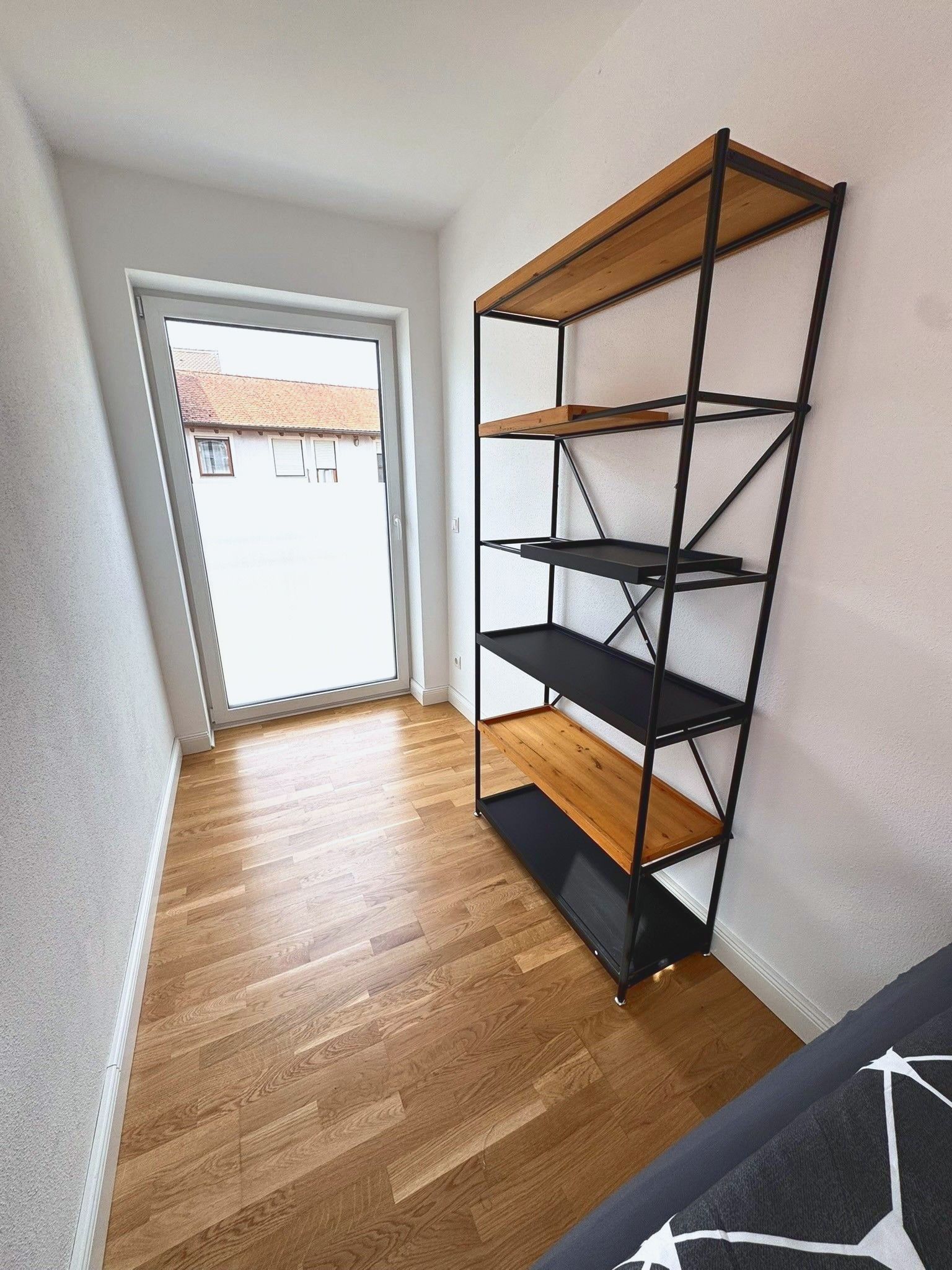 Schlafzimmer 2 mit offenem Regal aus Holz und Metall vor der Fenstertür