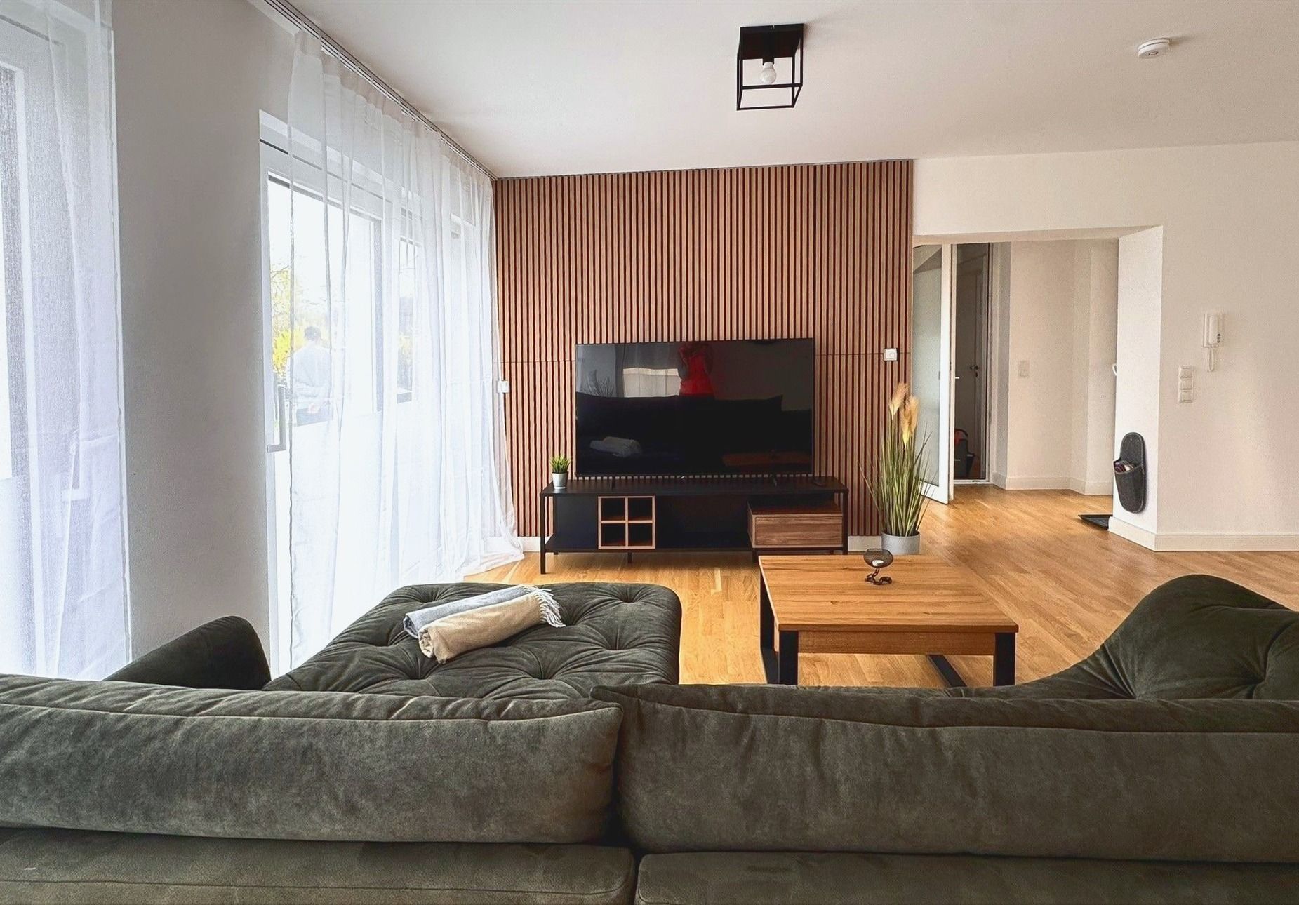 Blick vom Sofa auf Smart TV und Holzlamellenwand